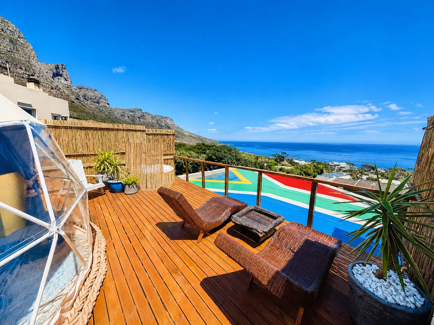 Geodesic dome on a timber deck with bamboo loungers and an ocean view