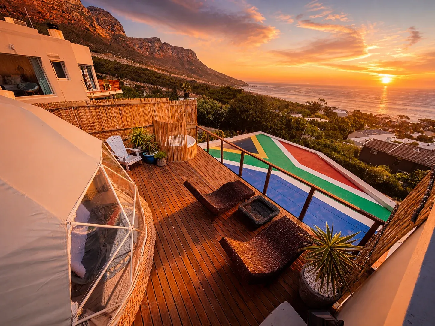 White geodesic dome on a timber deck above the Atlantic at sunset